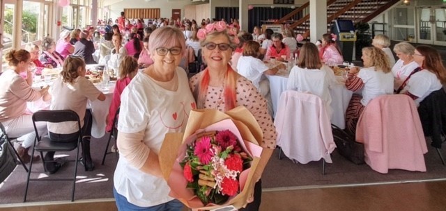 Debra, left, presents flowers to a breast cancer survivor at her Pink Ribbon Breakfast